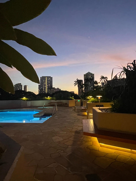 Dusk sky over a Honolulu pool deck with city skyline
